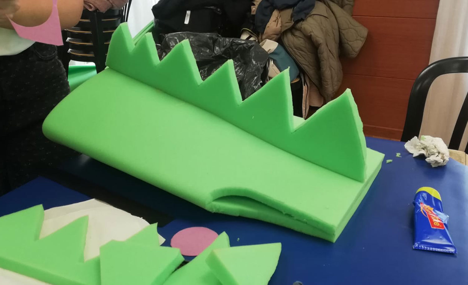 Plancha de espuma verde cortada en forma de cresta dentada y una pieza de cola para un disfraz