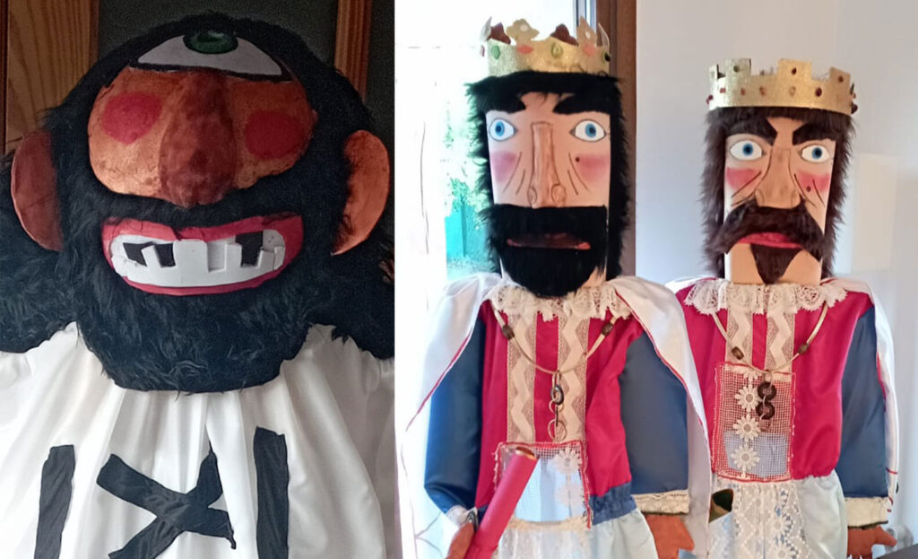 Cabezudos con espuma, uno de pelo negro con un solo ojo verde y dientes blancos, junto a dos cabezudos de reyes con corona y barba
